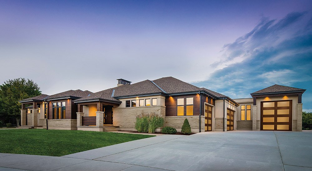 Modern home with warm wood-look garage doors at dusk